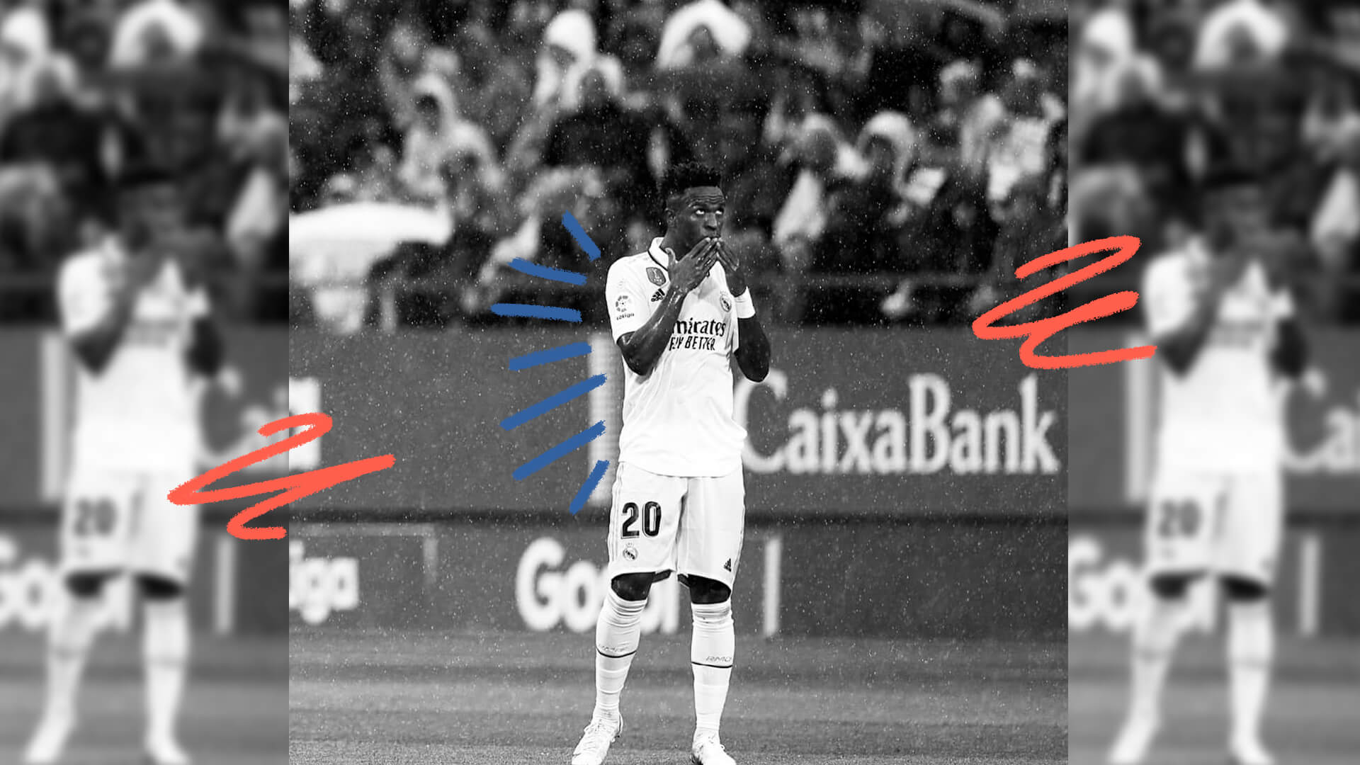 Imagem em preto e branco do jogador Vini Jr de costas para a arquibancada, em um estádio de futebol.