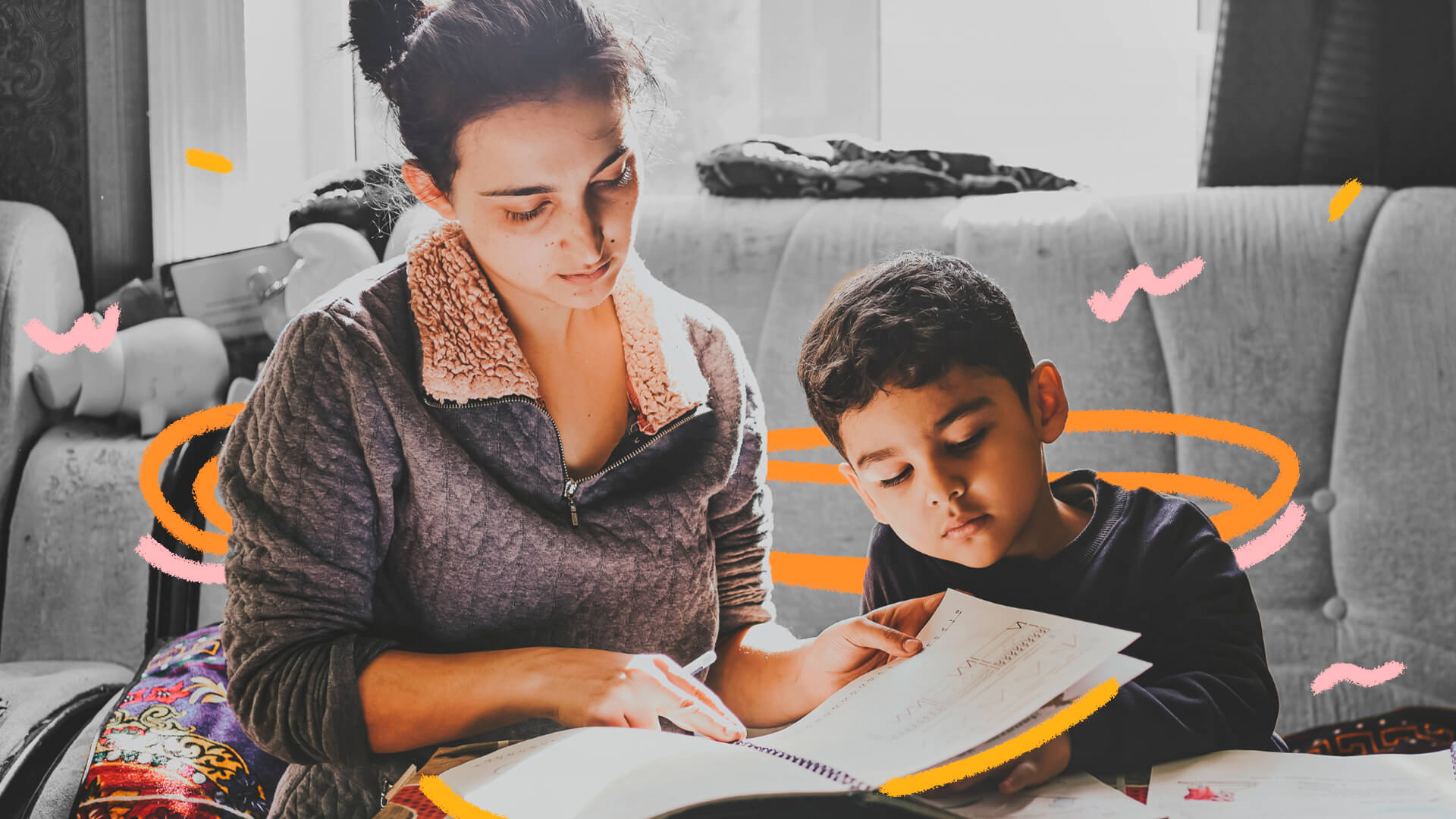 Mãe e filho olham para um caderno. A imagem possui intervenções de rabiscos coloridos.