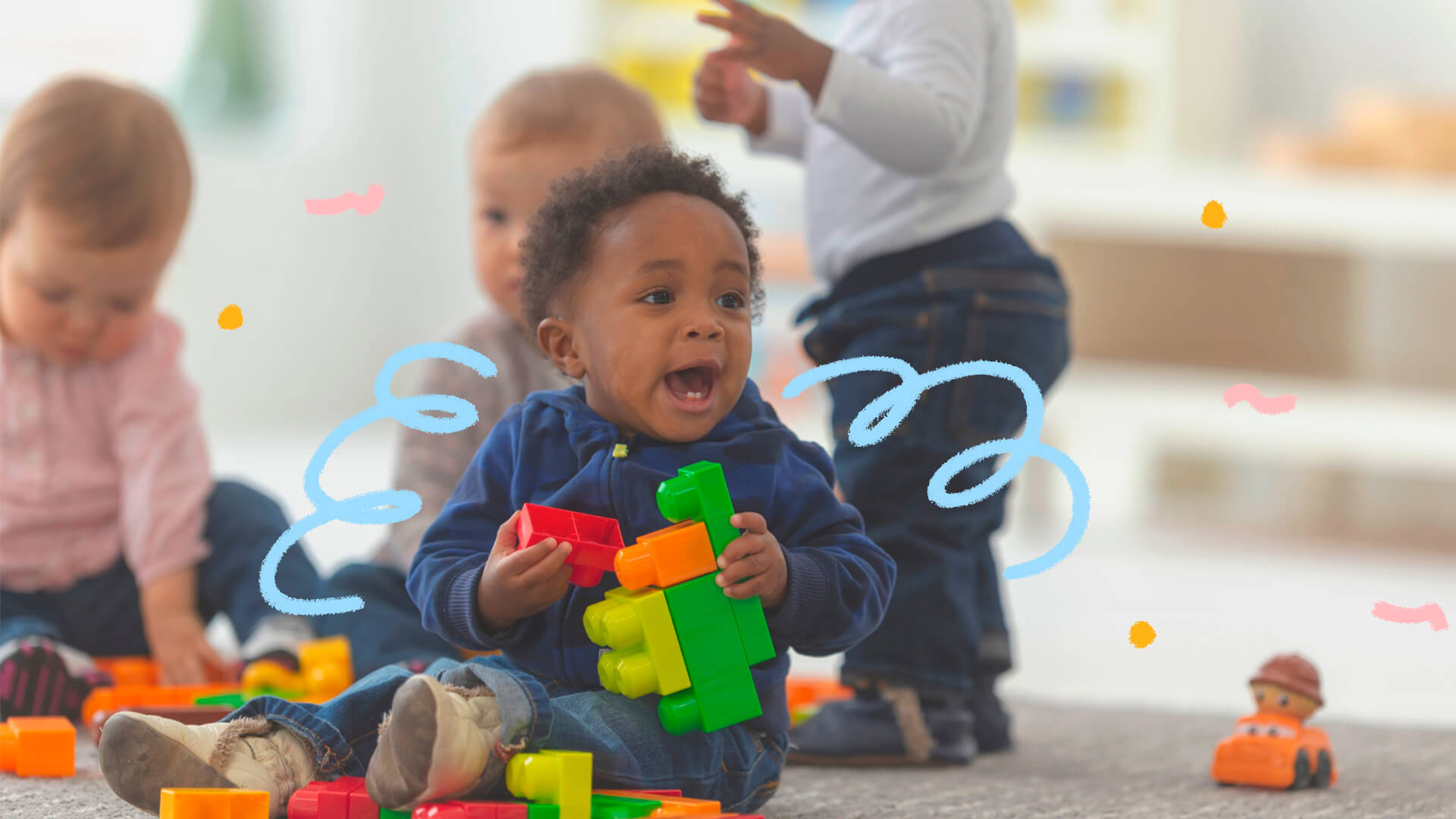 Foto de um bebê brincando com peças coloridas de montar. Ele é negro e usa roupa azul escuro. Atrás dele, tem outros bebês. A matéria é sobre os marcos do desenvolvimento infantil.