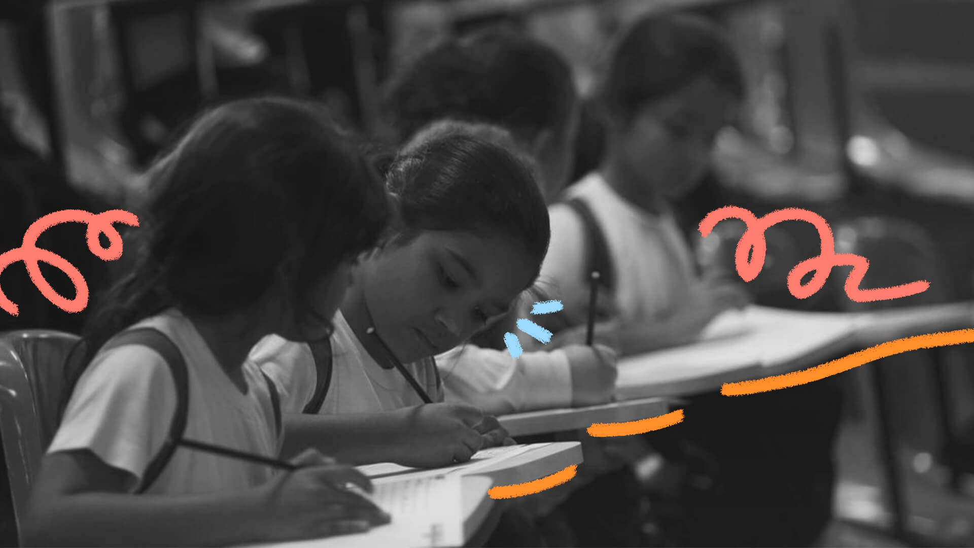Imagem em preto e branco mostra duas meninas sentadas em sala de aula escrevendo com lápis em seus cadernos