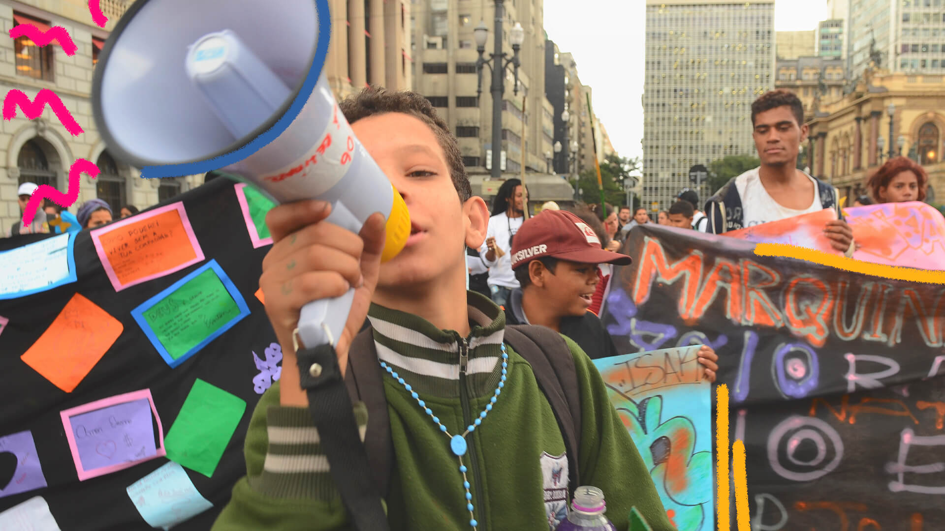 Na imagem, um menino de pele clara fala em um megafone. A imagem ilustra uma matéria sobre crianças em protestos.