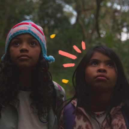 Foto de duas meninas indígenas na floresta, olhando para cima. A imagem é do filme “Para’í” (2018), de Vinicius Toro, e ilustra matéria sobre a Ciranda de Filmes 2023.