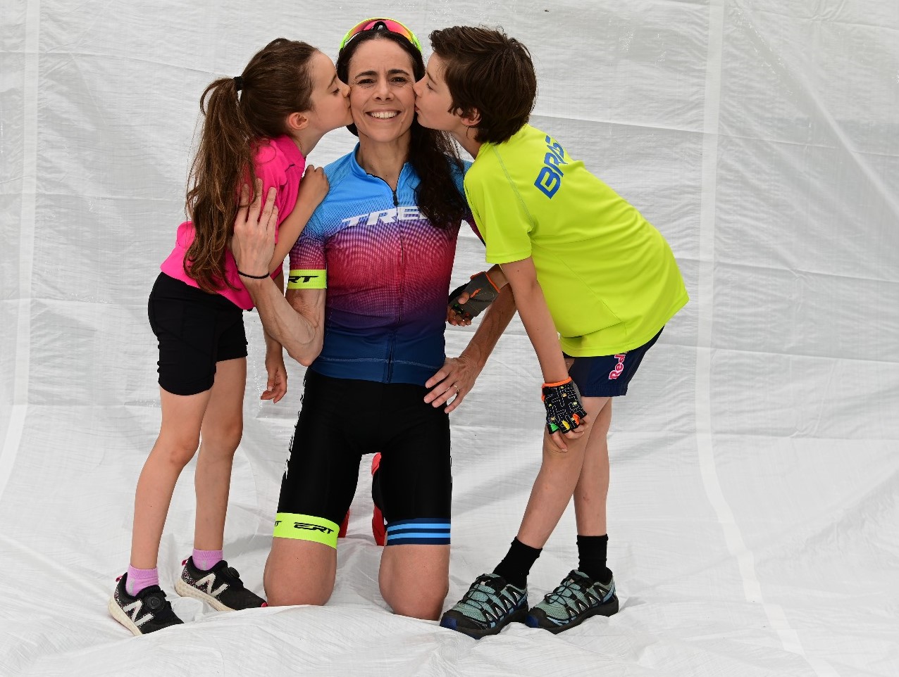 Na imagem, a atleta Jaqueline Mourão posa com os filhos, Ian e Jade, que a beija no rosto. 