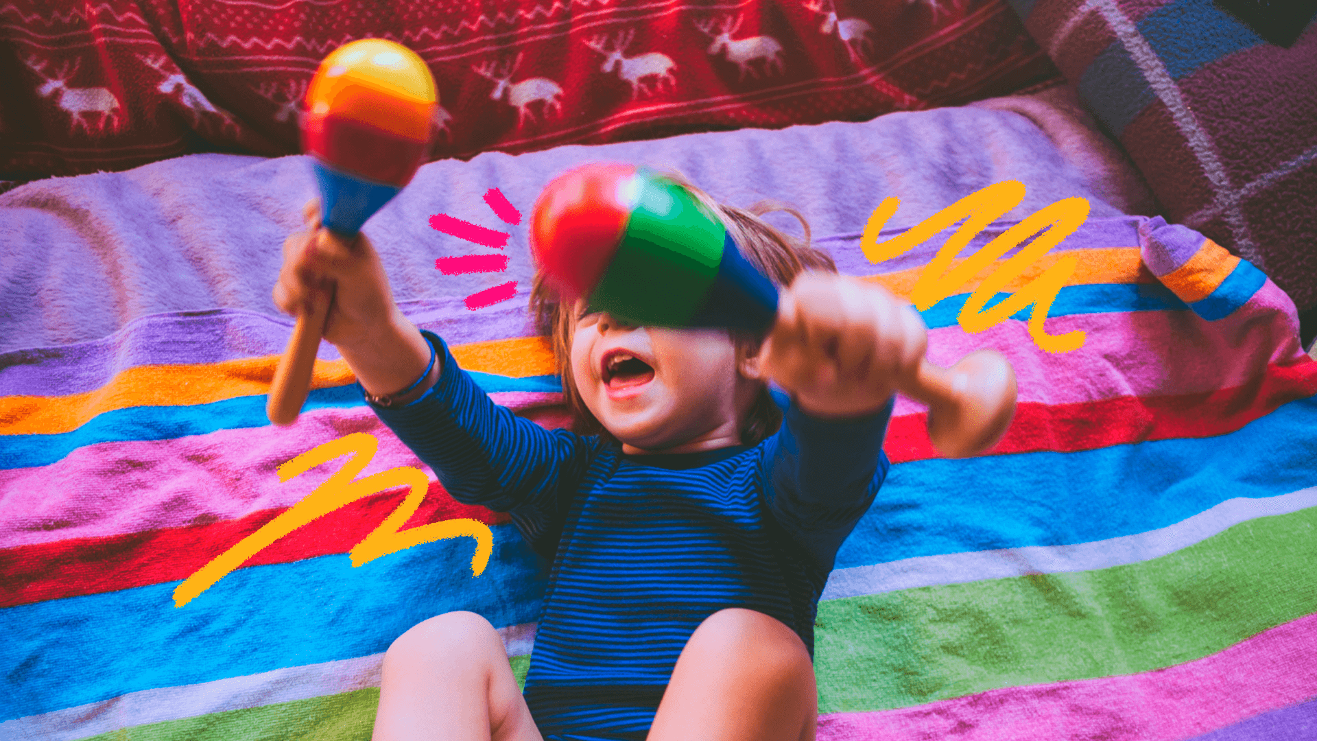Um menino está segurando um chocalho colorido em cada mão