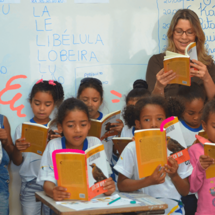imagem da matéria sobre os desafios para a educação brasileira mostra um grupo de ciranças vestidas de uniforme, em uma sala de aula, lendo livros.