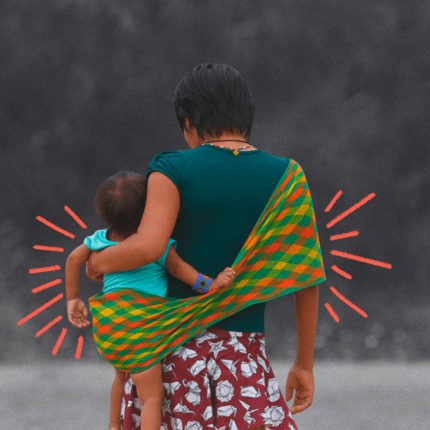Imagem ilustra matéria sobre a situação atual das crianças yanomami. Um amulher indígena está de costas carregando um bebê em um sling indígena.