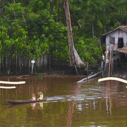 imagem ilustra matéria sobre os casos de exploração sexual no marajó e mostra uma paisagem ribeirinha, com crianças em uma canoa no meio de um rio e uma casa de madeira ao fundo.