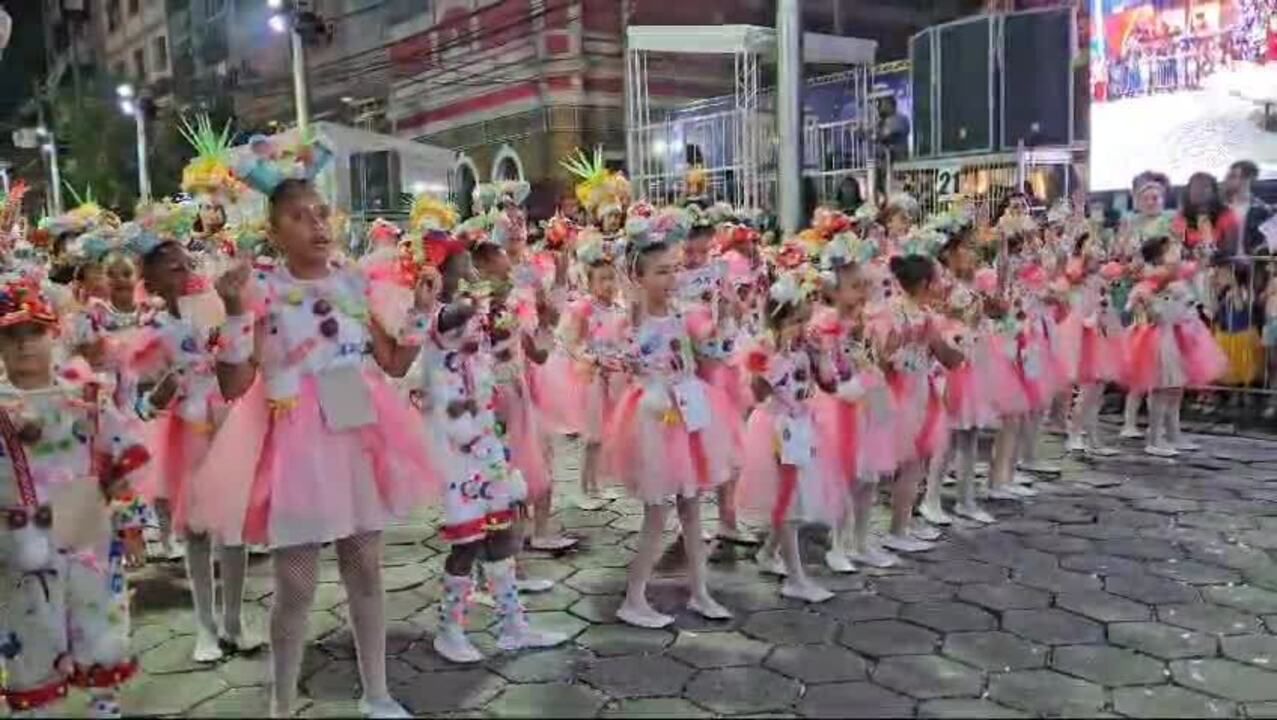Crianças vestidas com fantasias coloridas estão enfileiradas no desfile da ala das crianças 