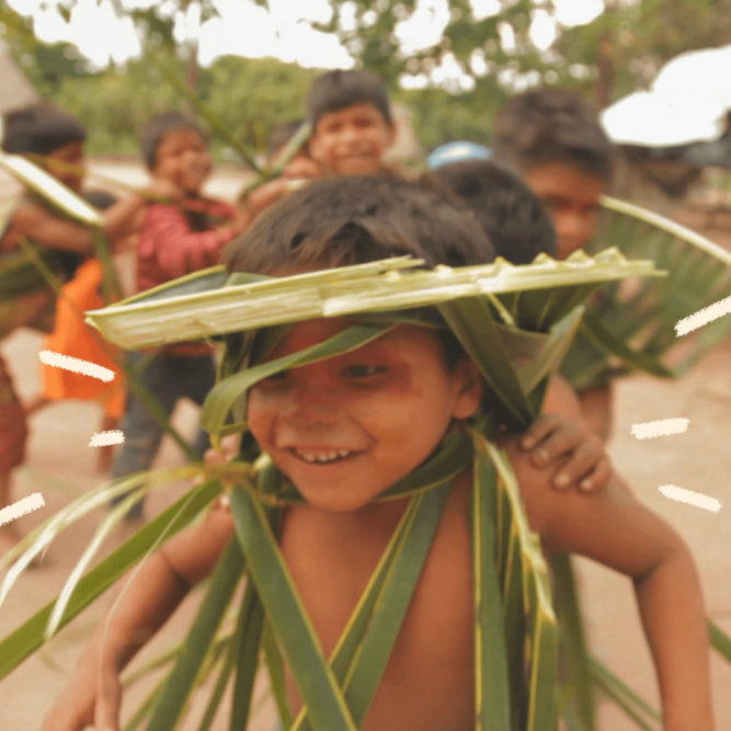 Um menino puxa uma fila de crianças indígenas que brincam na aldeia.