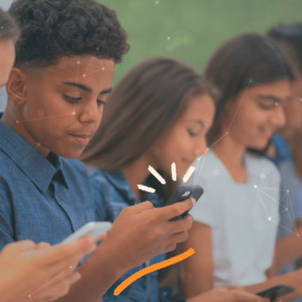 Um grupo de crianças estão sentados lado a lado e cada um olha para uma tela de celular
