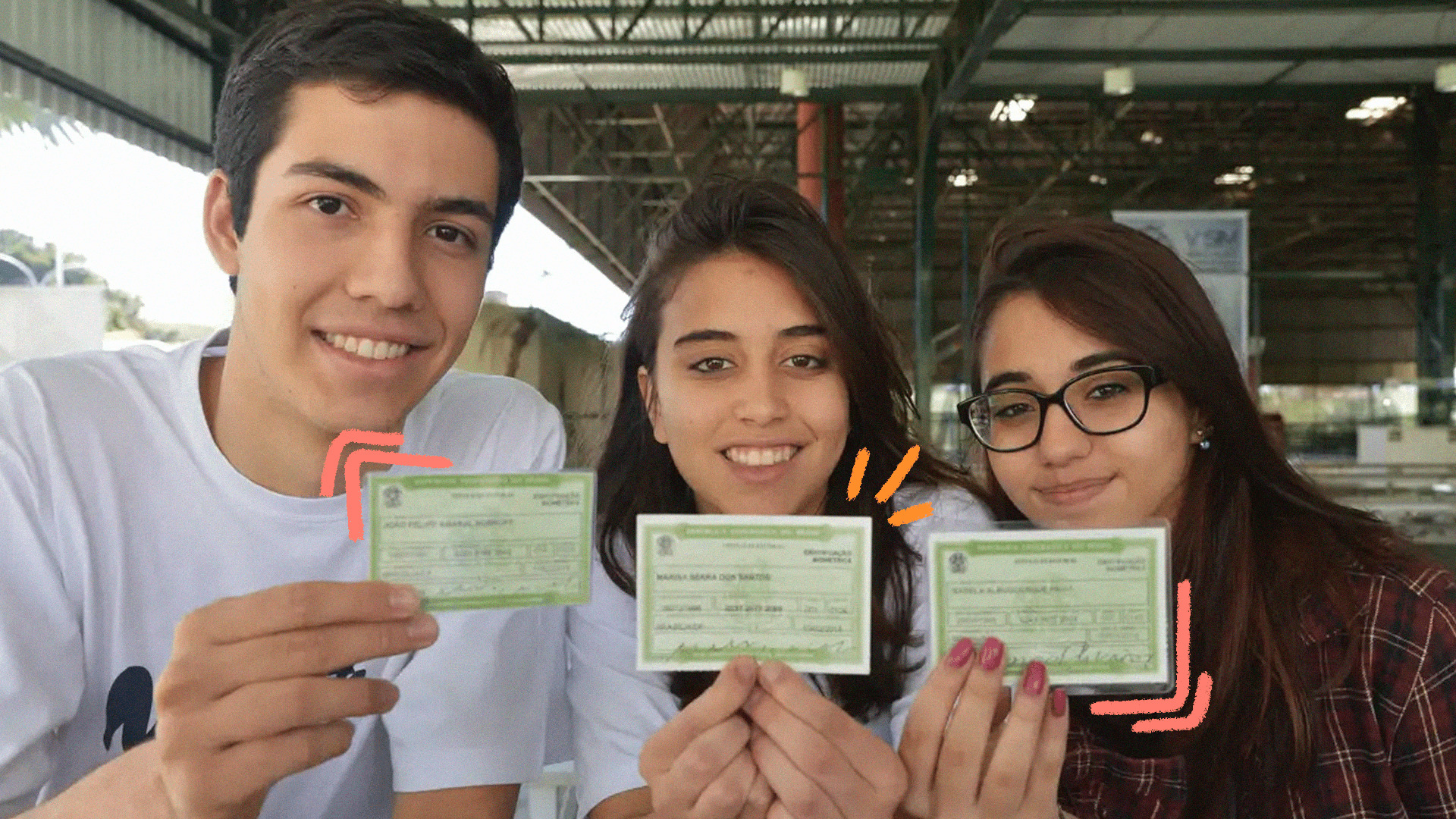 imagem de capa de matéria sobre o primeiro título de eleitor mostra três adolescentes, um menino de cabelos curtos e duas meninas de cabelos compridos em um pátio de escola. Todos seguram o documento de eleitor nas mãos.