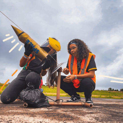 imagem mostra duas meninas adolesecentes construindo foguete e preparando o lançamento