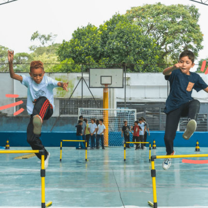 imagem de capa sobre o prˆmio de melhor escola do mundo mostra crianças pulando obstáculos em uma pista de atletismo