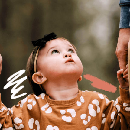 imagem de capa para matéria sobre guarda compartilhada e paternidade mostra uma menina branca, com menos de três anos, usando roupa floris e olhando para cima, segurando a mão de pessoas diferentes