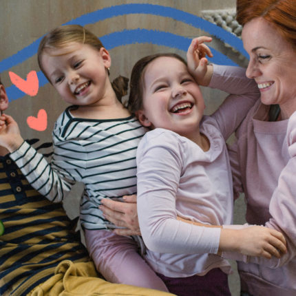 Imagem para matéria sobre irmão do meio mostra uma mulher branca, de cabelos ruivos e curtos deitada e abraçada com três crianças brancas sorridentes, um menino e duas meninas