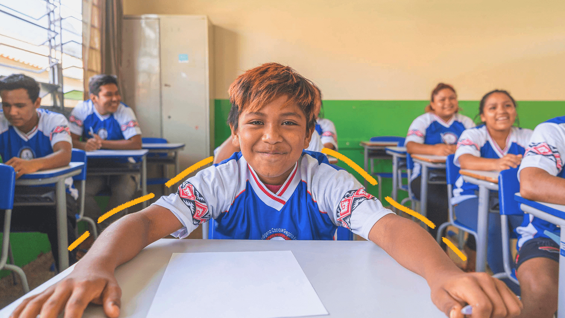 Imagem de capa para matéria sobre línguas indígenas mostra uma sala de aula em uma escola indígena. Em destaque, um estudante menino, pardo, com traços indígenas e cabelos curtos e uniforme escolar.