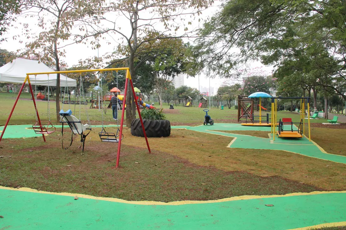 Imagem de parques inclusivos mostra o espaço do Ceret ao ar livre, com gramado verde, brinquedos coloridos com balanço para cadeirante e outros equipamentos. 