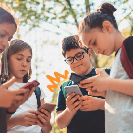 Um grupo de adolescentes está reunido e todos olham para a tela dos respectivos celulares. A matéria fala sobre o Jogo do Tigrinho nas escolas.