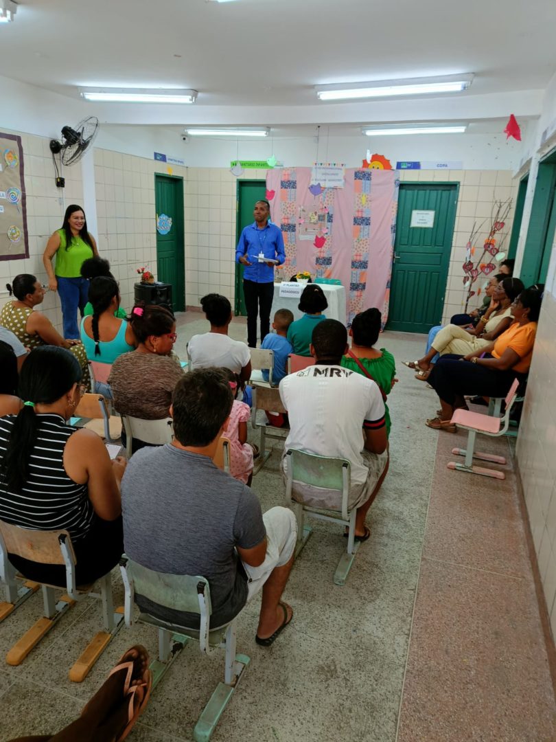 Imagem mostra reunião de escola e famílias em uma sala de aula.