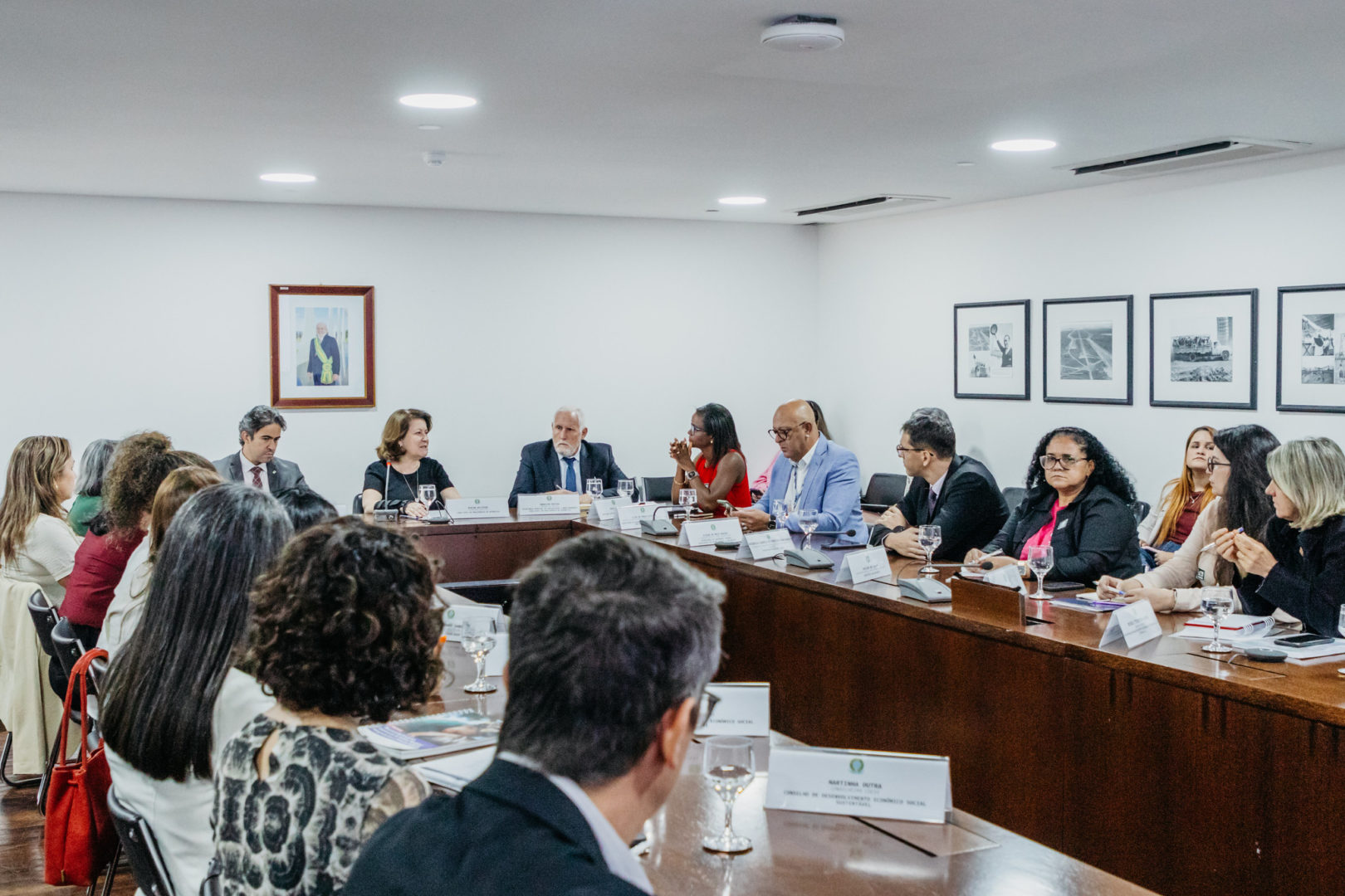 Imagem mostra uma reunião de homens e mulheres que fazem parte do comitê interministerial. Eles estão sentados e reunidos em uma sala, sentados lado a lado para discurtir pautas para beneficiar crianças e gestantes.