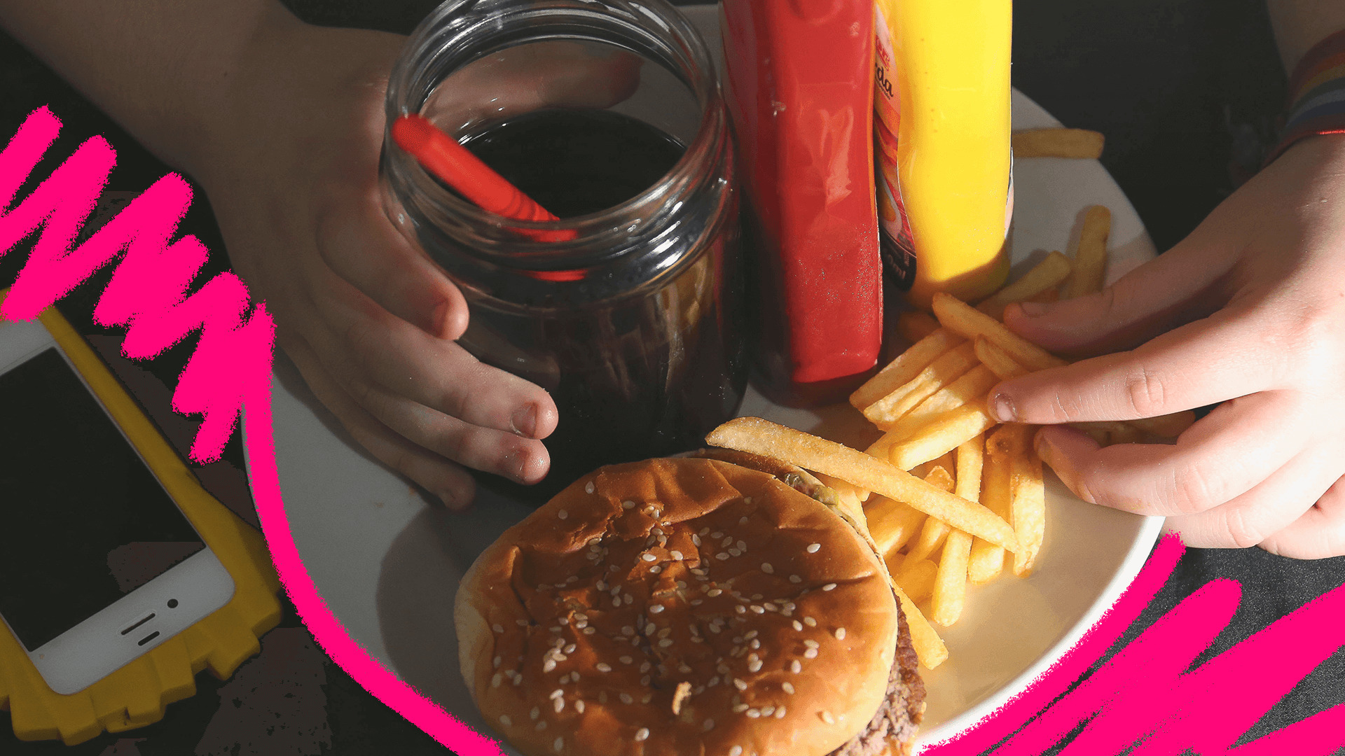 Imagem de capa para matéria sobre ultraprocessados mostra mãos de crianças segurando um prato com hambúrguer, batata frita e refrigerante.