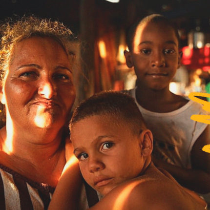 Imagem mostra uma família atingida pela tragédia de Brumadinho. Em close, uma mulher e duas crianças, dois meninos negros olhando para a câmera.