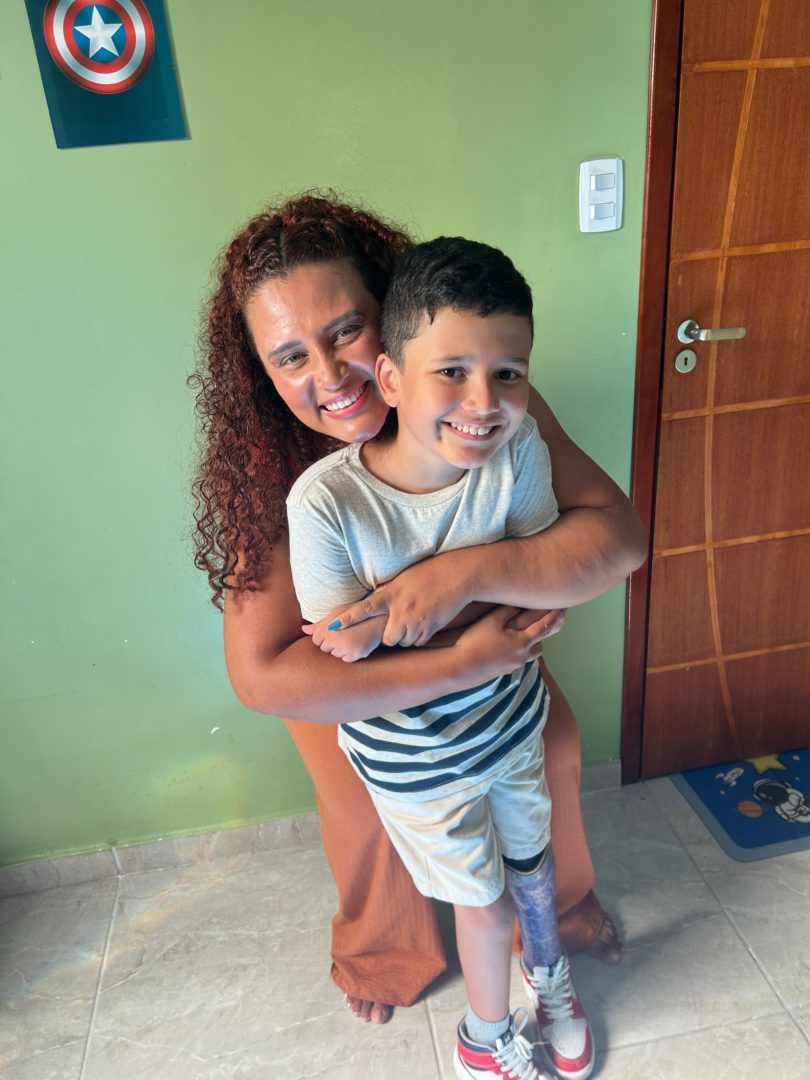 Mães de filhos com deficiência: Imagem mostra uma muher abraçando um menino em uma casa.