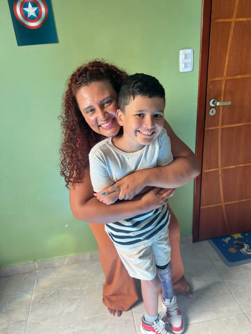 Mães de filhos com deficiência: Imagem mostra uma muher abraçando um menino em uma casa.