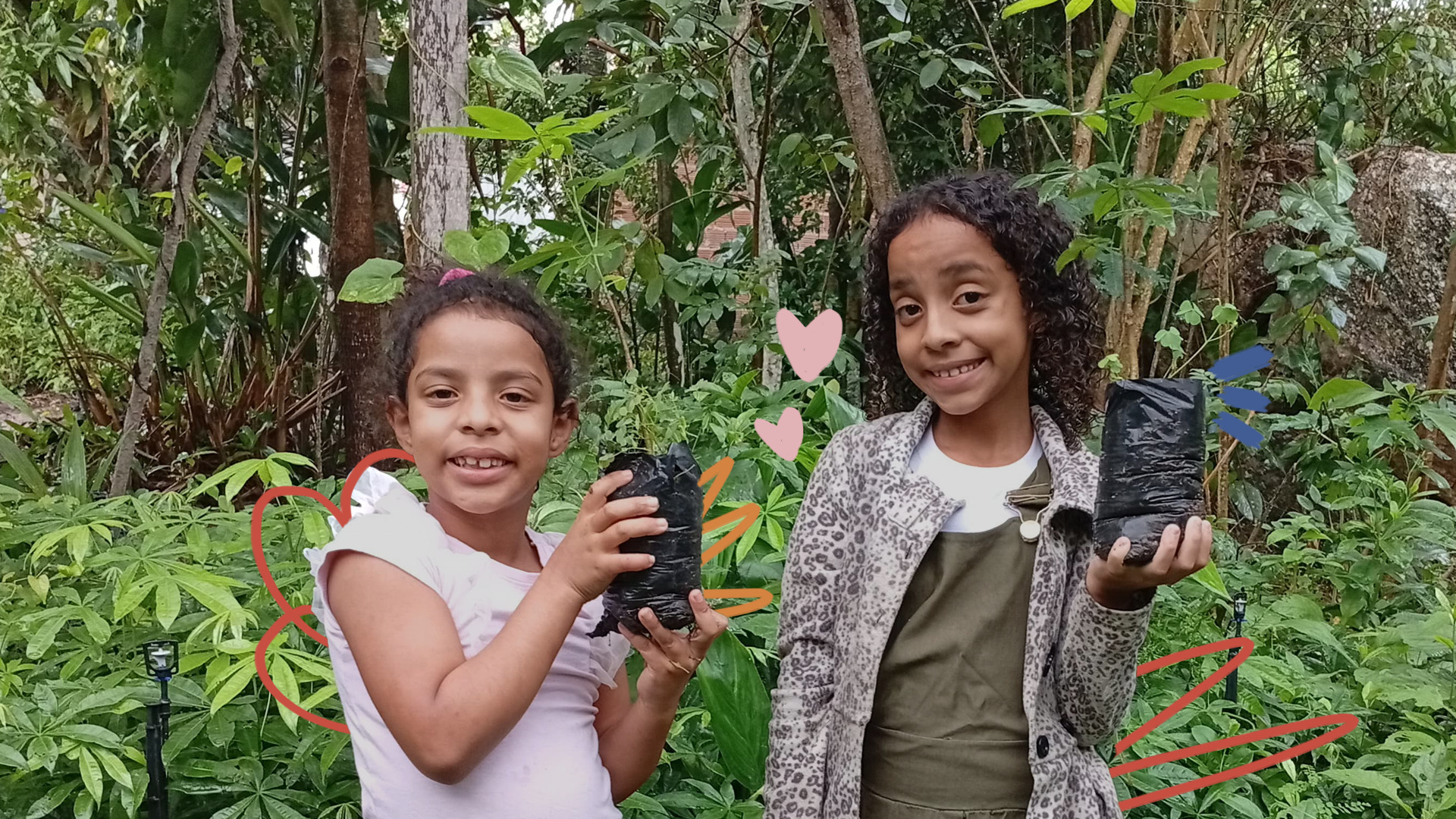 Imagem mostra duas crianças Xucuru de Ororubá: duas meninas negras de cabelos cacheados segurando mudas de plantas.