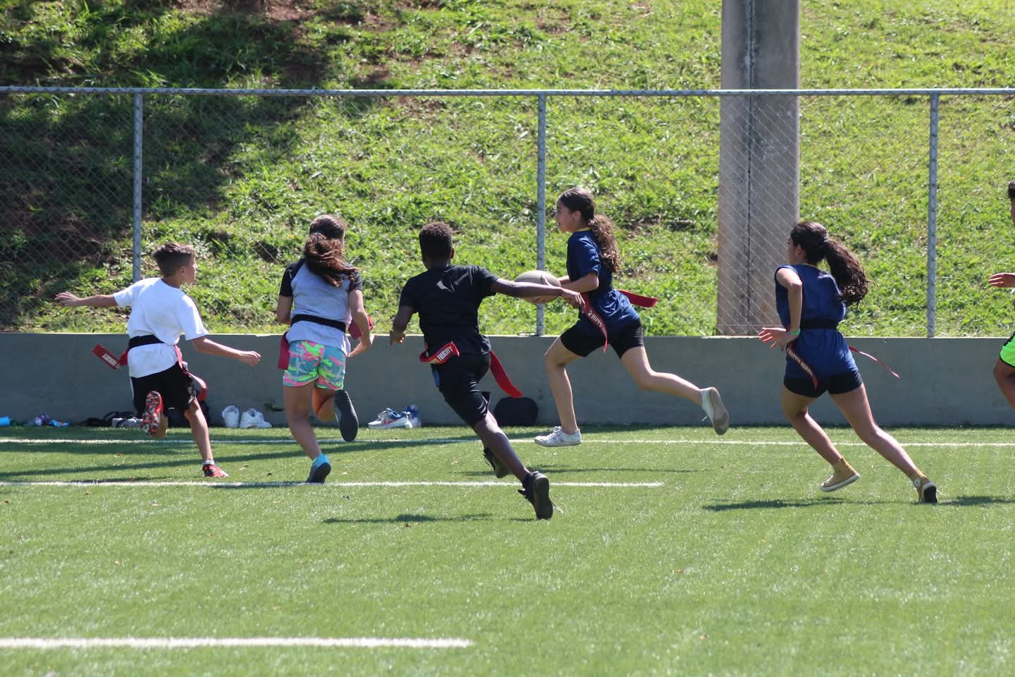 Imagem mostra turma de adoelscentes jogando rugby em um gramado.