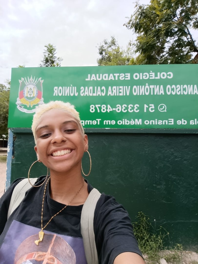 Imagem mostra uma adolescente negra, de cabelos curtos loiros sorrindo para uma selfie.