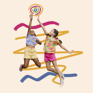 Imagem mostra duas meninas brincando de bola. As duas vestem roupas coloridas. A matéria traz uma série de sugestões do que fazer com as crianças em casa nas férias.