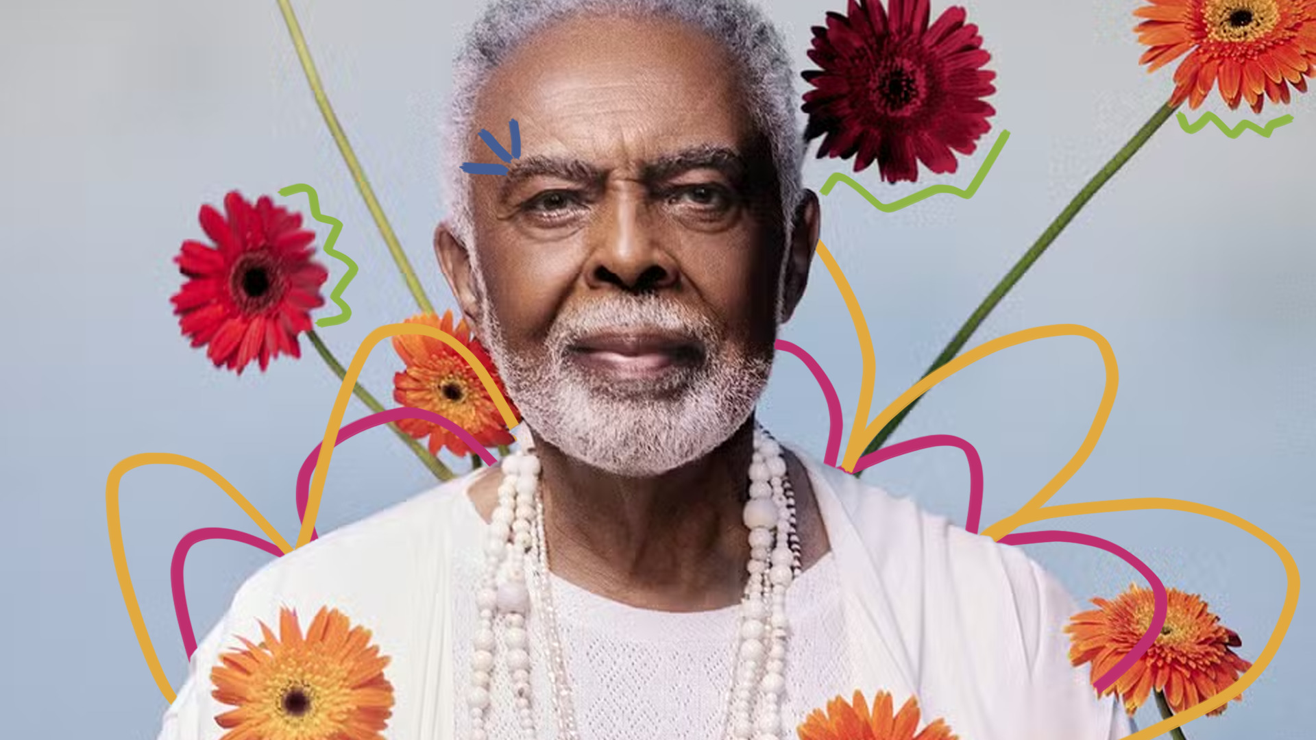 Imagem mostra o cantor Gilberto Gil em um cenário com flores coloridas.