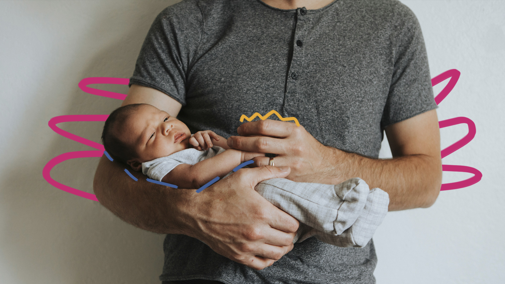 O tronco de um homem vestindo camiseta cinza escuro com botões e suas mãos que seguram um bebê recém-nascido de macacão claro.