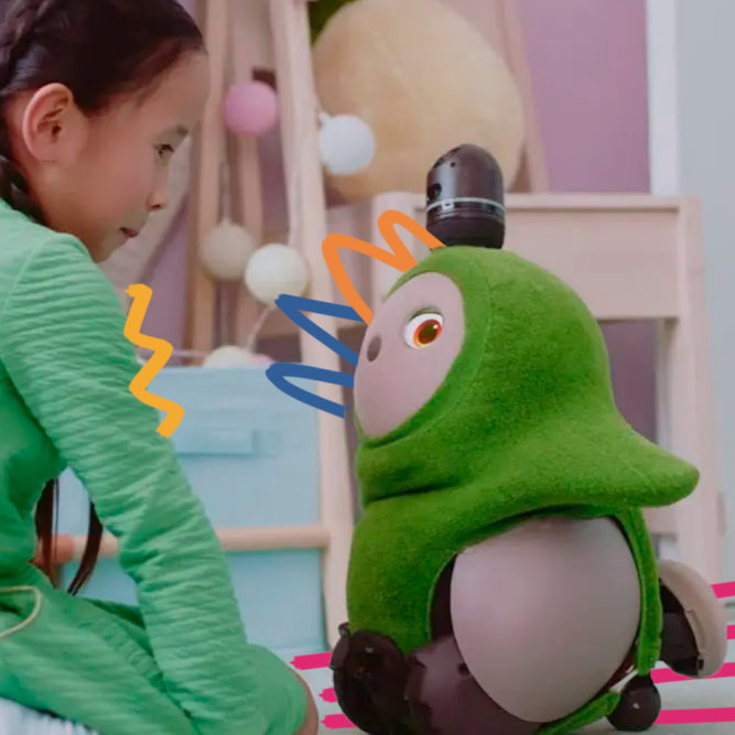 Brinquedos com IA: Imagem mostra uma menina brincando com um robô Lovot verde.
