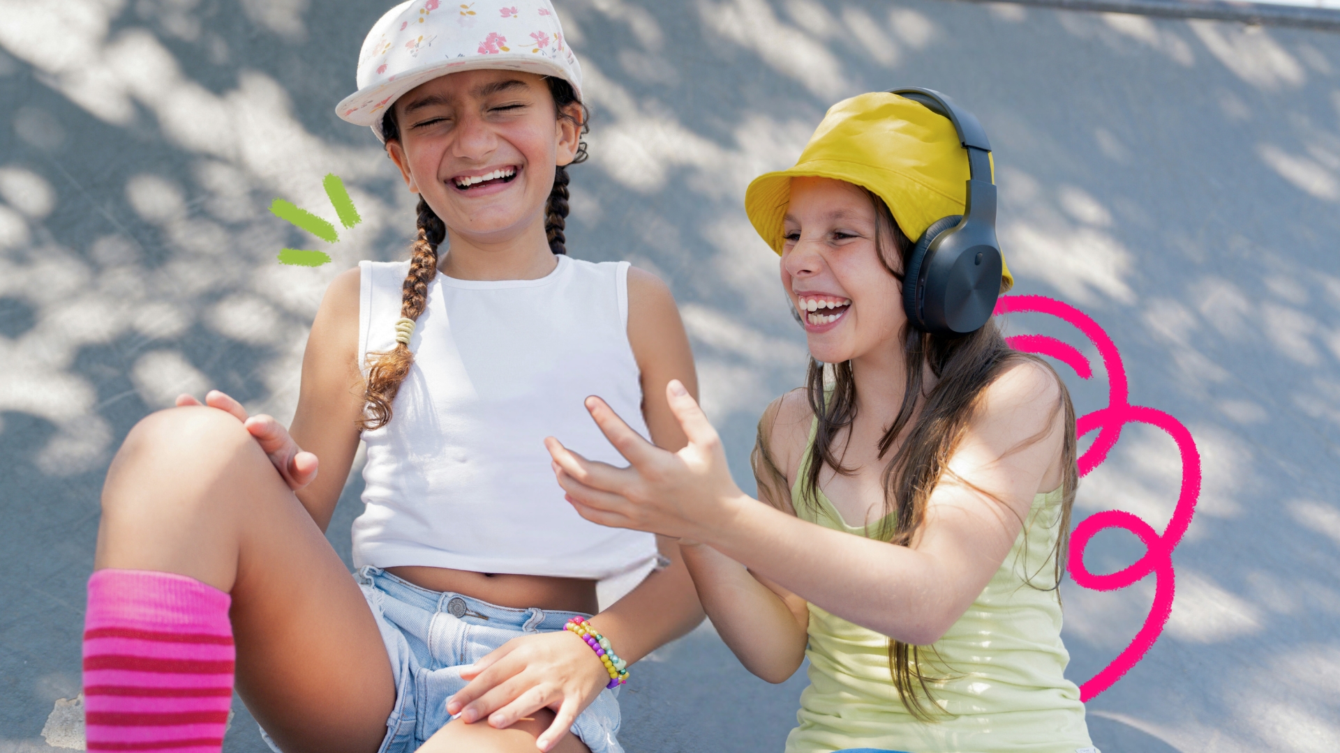 Imagem mostra duas crianças rindo. Uma veste camiseta e boné brancos, shorts jeans e meia rosa. A outra veste camiseta e boné amarelos e usa um fone de ouvido preto. Elas parecem brincar fora das telas e se divertir com isso.