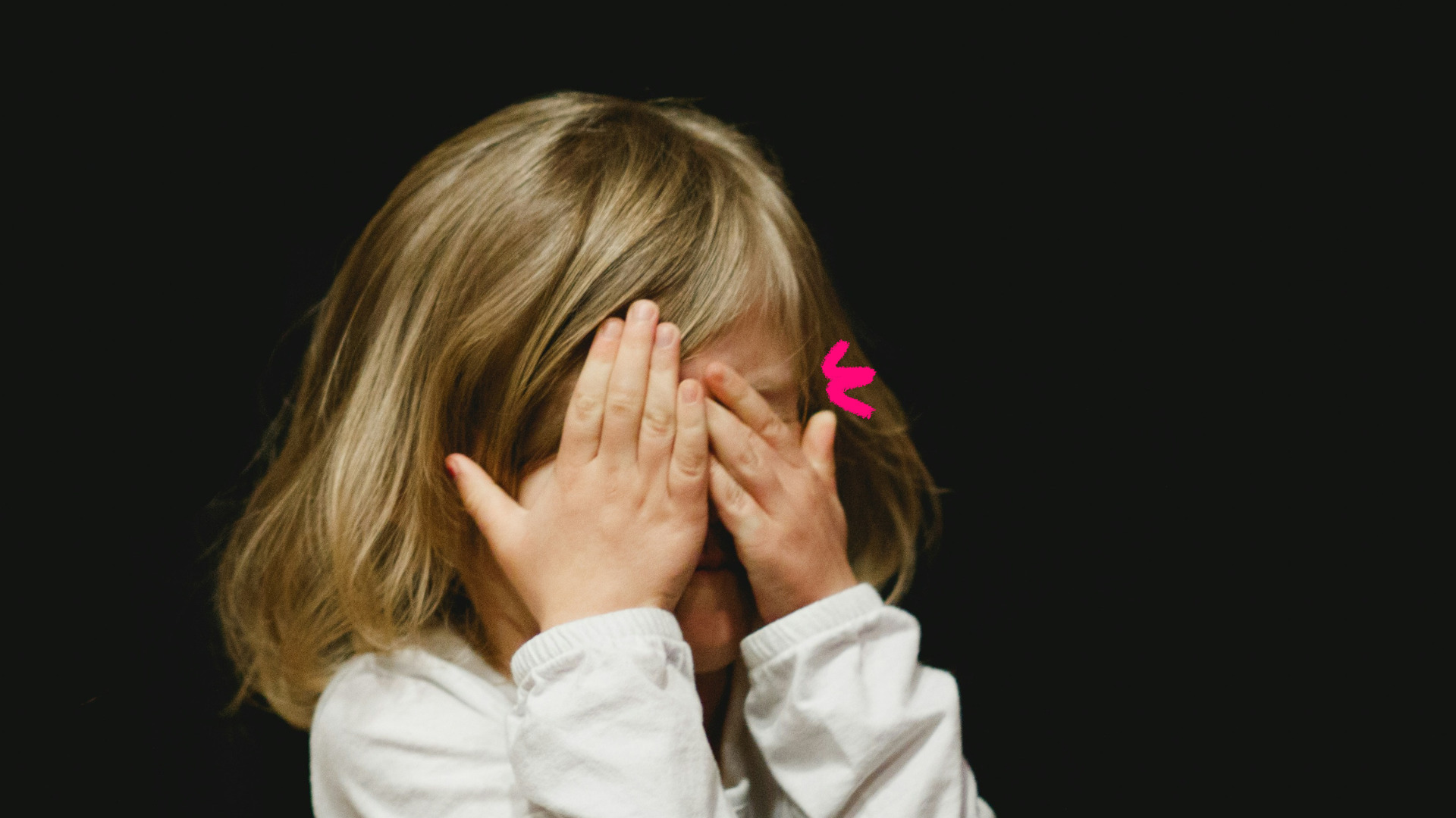 Imagem de capa de matéria sobre as diferenças enter bullying ou birra mostra uma menina branca de cabelos lisos com as mãos no rosto.