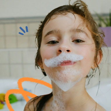 Imagem de capa para matéria sobre hgiene pessoal das crianças mostra uma menina branca, de cabelos molhados e espuma no rosto.