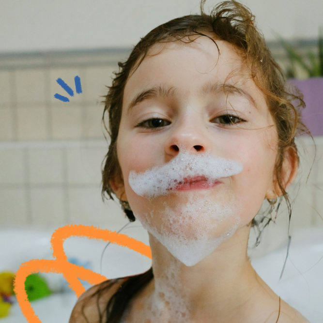 Imagem de capa para matéria sobre hgiene pessoal das crianças mostra uma menina branca, de cabelos molhados e espuma no rosto.