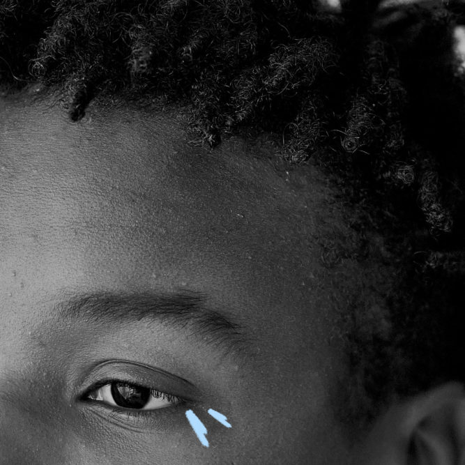 Imagem de capa para matéria sobre racismo na escola mostra a metade do rosto de um menino negro e riscos coloridos perto dos olhos.