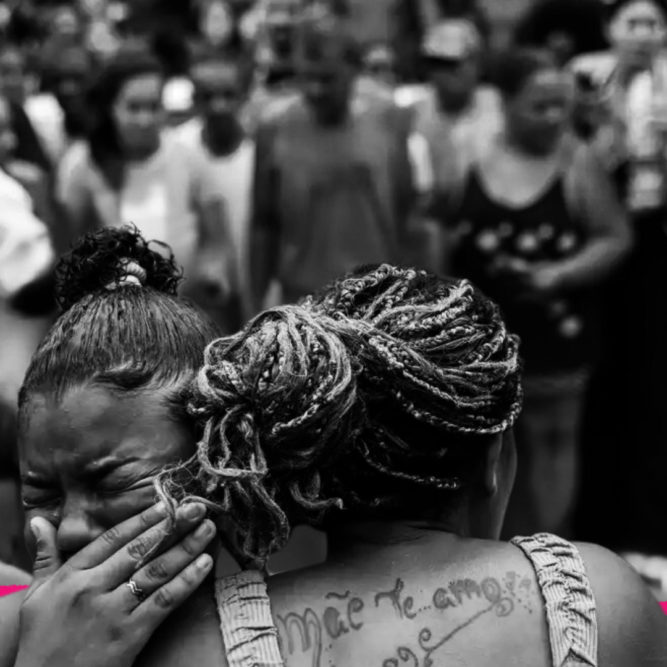 Foto em preto e branco mostra duas mulheres se abraçando. A matéria fala de segurança pública para as crianças da favela depois da mais recente operação policial no Rio de Janeiro.