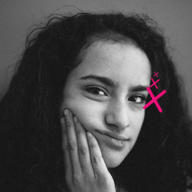 Imagem mostra retrato em preto e branco de uma garota com cabelo cacheado, expressão pensativa e leve sorriso. Ela apoia o rosto em uma das mãos, enquanto um desenho digital em rosa, em forma de “X” com pequenos traços, aparece próximo ao seu olho direito. O fundo é neutro. Imagem ilustra reportagem sobre a hora certa do primeiro celular na infância.