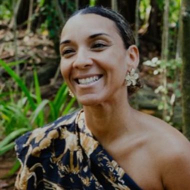 Imagem mostra foto de Silvane Vasconcelos, uma mulher negra. Ela está com cabelos presos, vestido de um ombro só florido e sorri para a foto. Ela fala sobre a importância da representatividade.