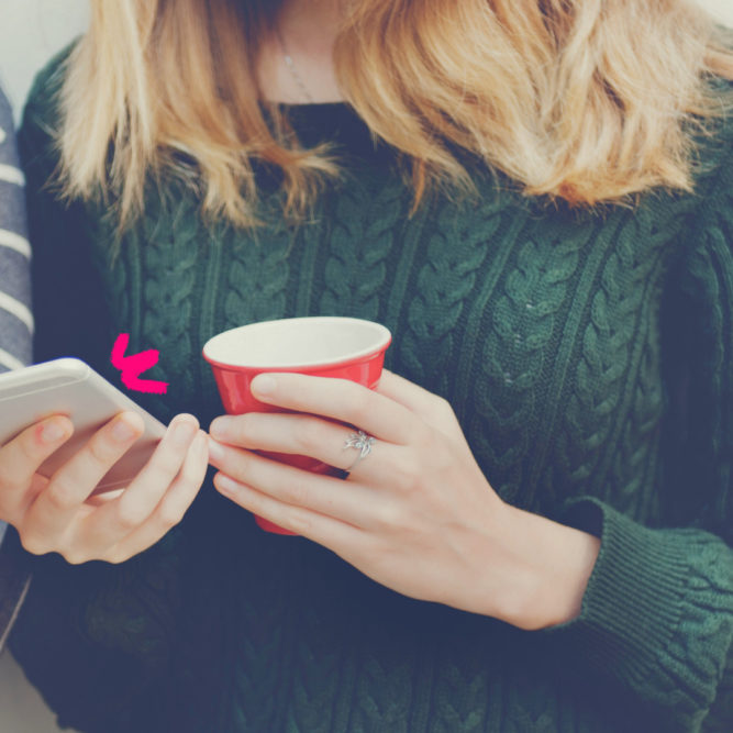 Imagem mostra apenas as mãos de uma adolescente segurando uma xícara e um celular. Ela ilustra uma reportagem sobre redes sociais e infância