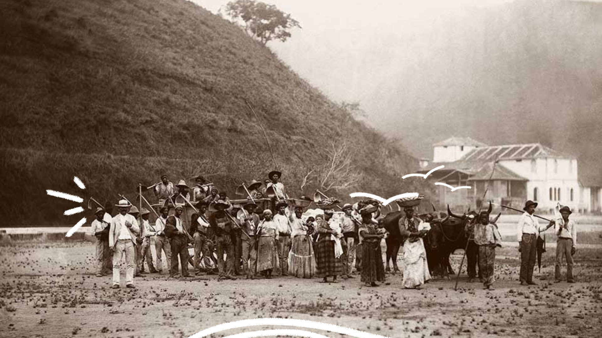 Fotografia antiga em preto e branco mostra um grupo de homens e mulheres negros reunidos em uma área aberta, alguns segurando ferramentas de trabalho e ao lado de bois de carga. Ao fundo, há uma encosta e construções antigas.