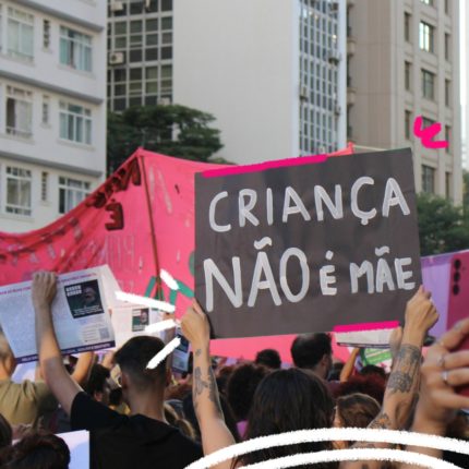 Pessoas em uma manifestação na rua com destaque para um cartaz onde se lê Criança não é mãe em referência a meninas vítimas de estupro