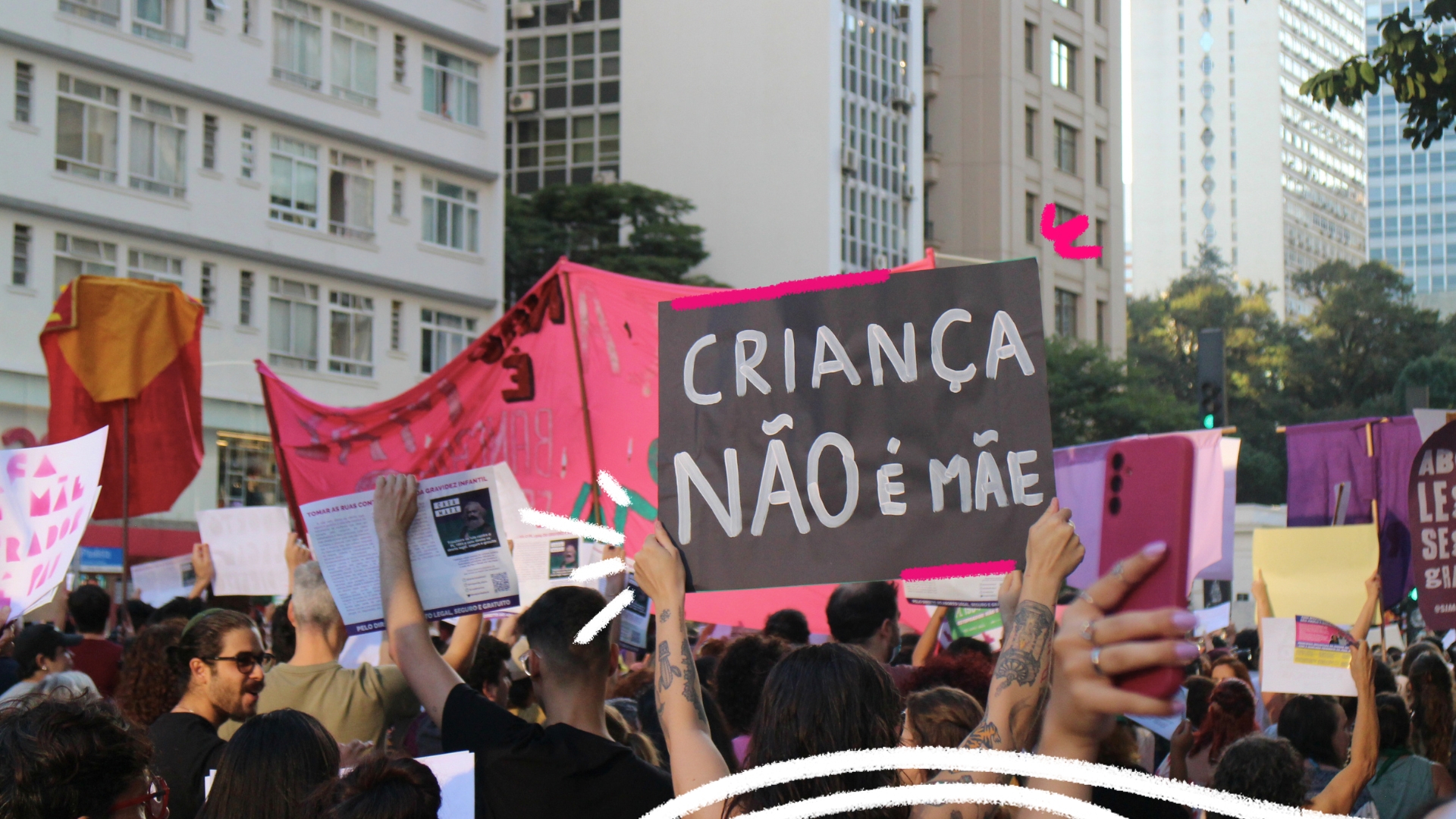 Pessoas em uma manifestação na rua com destaque para um cartaz onde se lê "Criança não é mãe" em referência a meninas vítimas de estupro