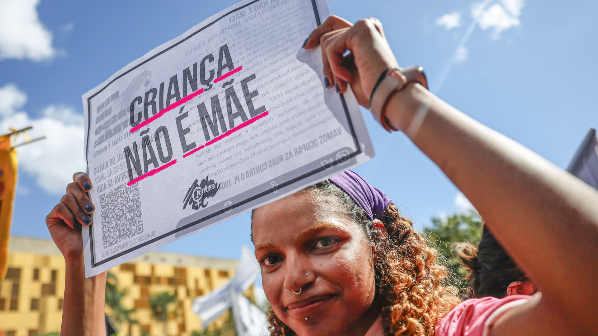 Uma mulher negra em uma manifestação na rua segura um cartaz onde se lê "Criança não é mãe" em referência a meninas vítimas de estupro