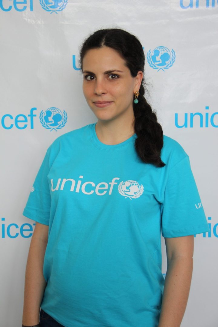 Luiza Teixeira, especialista de proteção à criança do UNICEF no Brasil, posa diante de um painel com a marca da organização.